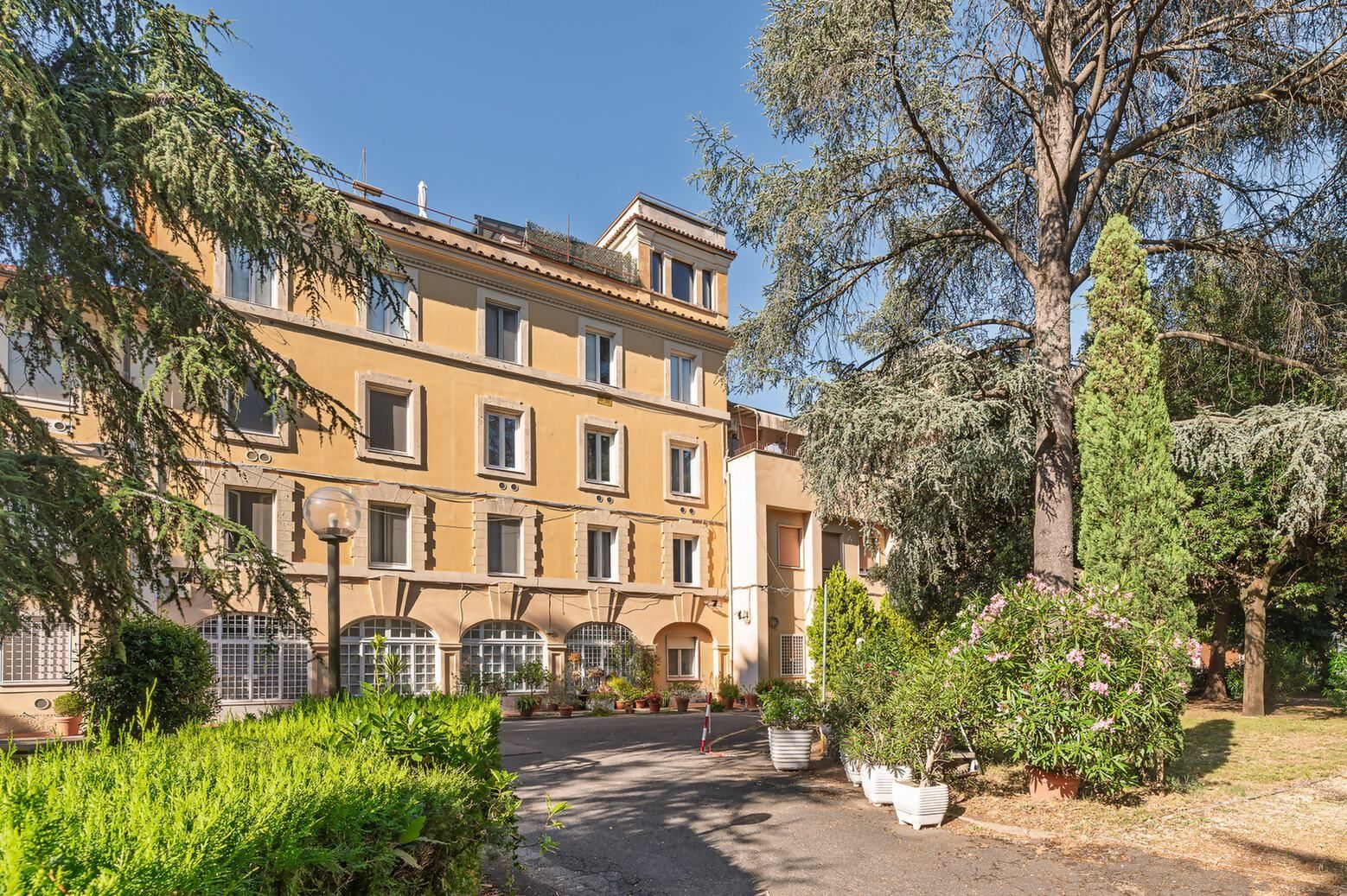 Un edificio a più piani con un cortile centrale, circondato da verde e alberi.