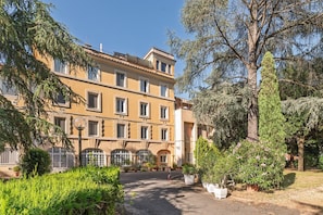 A multi-story building with a central courtyard, surrounded by greenery and trees.