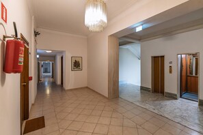 A hallway with a fire extinguisher, a framed picture, and an elevator.