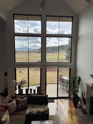 Ein Wohnzimmer mit großem Fenster, einer Couch, einem Couchtisch und einem Kamin.