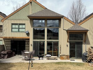 Ein zweistöckiges Haus mit Garage, großen Fenstern und einer Terrasse mit Gartenmöbeln.