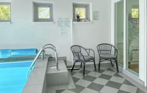 A pool area with a checkered floor, two wicker chairs, a pool ladder, and a window with a plant. - Lovely home in Hvide Sande with sauna (Hvide Sande)