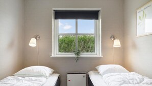 A bedroom with two single beds, a window with a view of greenery, and a wall-mounted air conditioner. - Lovely home in Hvide Sande with sauna (Hvide Sande)