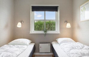 A bedroom with two single beds, a window with a view of greenery, and a wall-mounted air conditioner. - Lovely home in Hvide Sande with sauna (Hvide Sande)