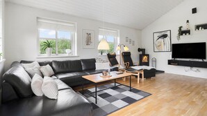 A modern living room with a leather sofa, a wooden coffee table, and a flat-screen TV. - Lovely home in Hvide Sande with sauna (Hvide Sande)