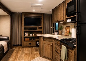 Una cocina compacta con armarios de madera, un microondas integrado y una estufa.