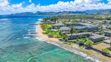 A coastal resort with beachfront villas, a marina, and a view of the ocean and mountains.