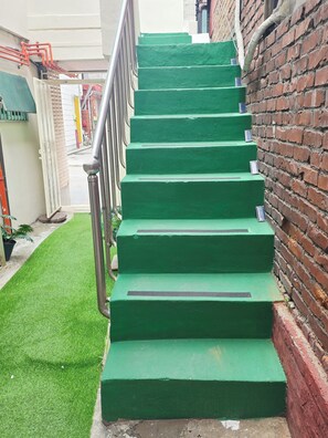 Eine Treppe in Grün mit Metallgeländern, die zu einem Hauseingang führt.