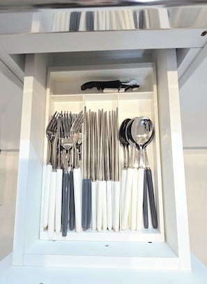 A drawer with neatly organized cutlery, including forks, knives, and spoons.