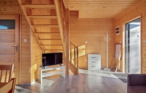 Ein Holzblockhaus-Innenraum mit Treppe, einem Fernseher, einem weißen Schrank und einem großen Fenster.