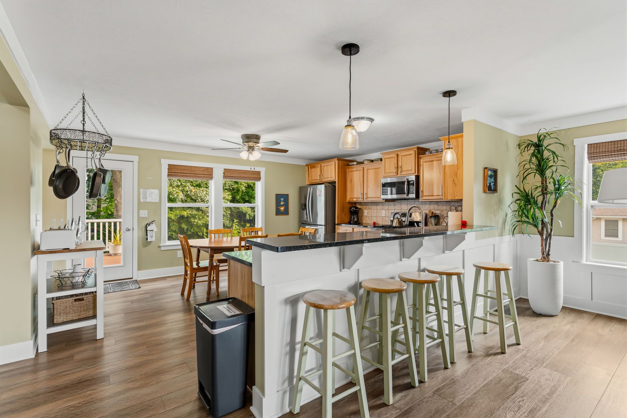 A modern kitchen with a central island, bar stools, and a dining area with a table and chairs.