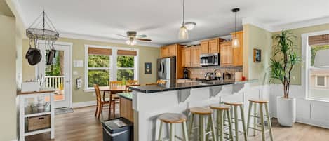 A modern kitchen with a central island, bar stools, and a dining area with a table and chairs.