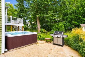 Un jardin avec un jacuzzi, un barbecue et une petite table.