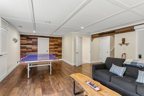 Un salon avec une table de ping-pong, un canapé et une table basse en bois.