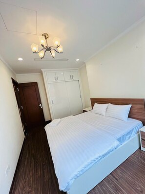 Ein Hotelzimmer mit einem Bett, einem Kleiderschrank, Holzboden und einer Deckenleuchte.