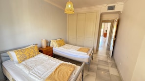 Une chambre avec deux lits, une table de chevet, une lampe et une armoire.