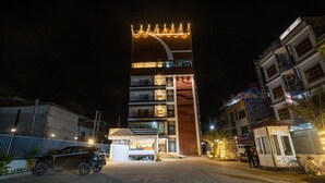 Ein mehrstöckiges Hotel mit markanter, gebogener Architektur und beleuchteter Beschilderung.