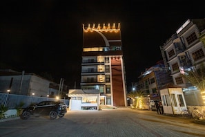 A multi-story hotel with a prominent curved structure and illuminated signage.
