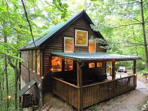 Eine Holzhütte mit Veranda, großen Fenstern und einer Satellitenschüssel.
