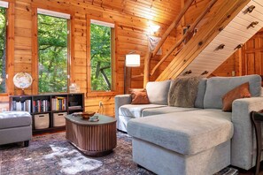Ein rustikales Holzhaus-Interieur mit einer Couch, einem Bücherregal und einem runden Couchtisch.