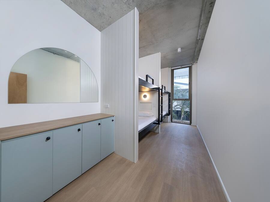 A narrow hallway with a bunk bed, a wooden cabinet, and a large mirror.