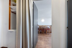 A room with a wooden floor, a table with chairs, and a white wall. - Apartment “Valmeinier Le Miras” with Mountain View, Private Terrace and Wi-Fi (Valmeinier)
