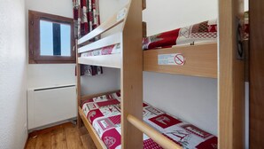 A bunk bed with a window, a radiator, and a notice on the bed. - Apartment “Valmeinier Le Miras” with Mountain View, Private Terrace and Wi-Fi (Valmeinier)