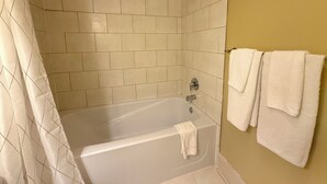 A bathroom with a bathtub, a showerhead, and a towel rack with towels. - Oceanfront Suite with Relaxing Tub & Private Bath - Rm 2 (Gabriola)