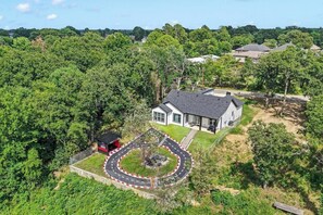 A house with a driveway and a small building with a red roof. - New Construction | Lake View Retreat (Gun Barrel City)