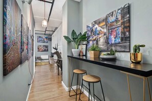 A modern hallway with art on the walls, a bar area with stools, and a plant on the counter. - Temple Court Suite in Melbourne CBD (Melbourne)