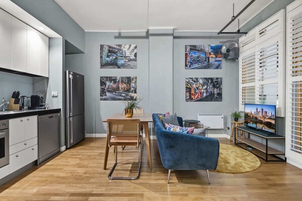 Eine moderne Küche mit Kühlschrank, ein Essbereich mit Stuhl und Tisch sowie eine Wohnbereich mit Sofa und Fernseher.