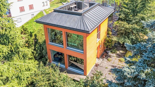 A modern house with a flat roof, large windows, and a balcony.