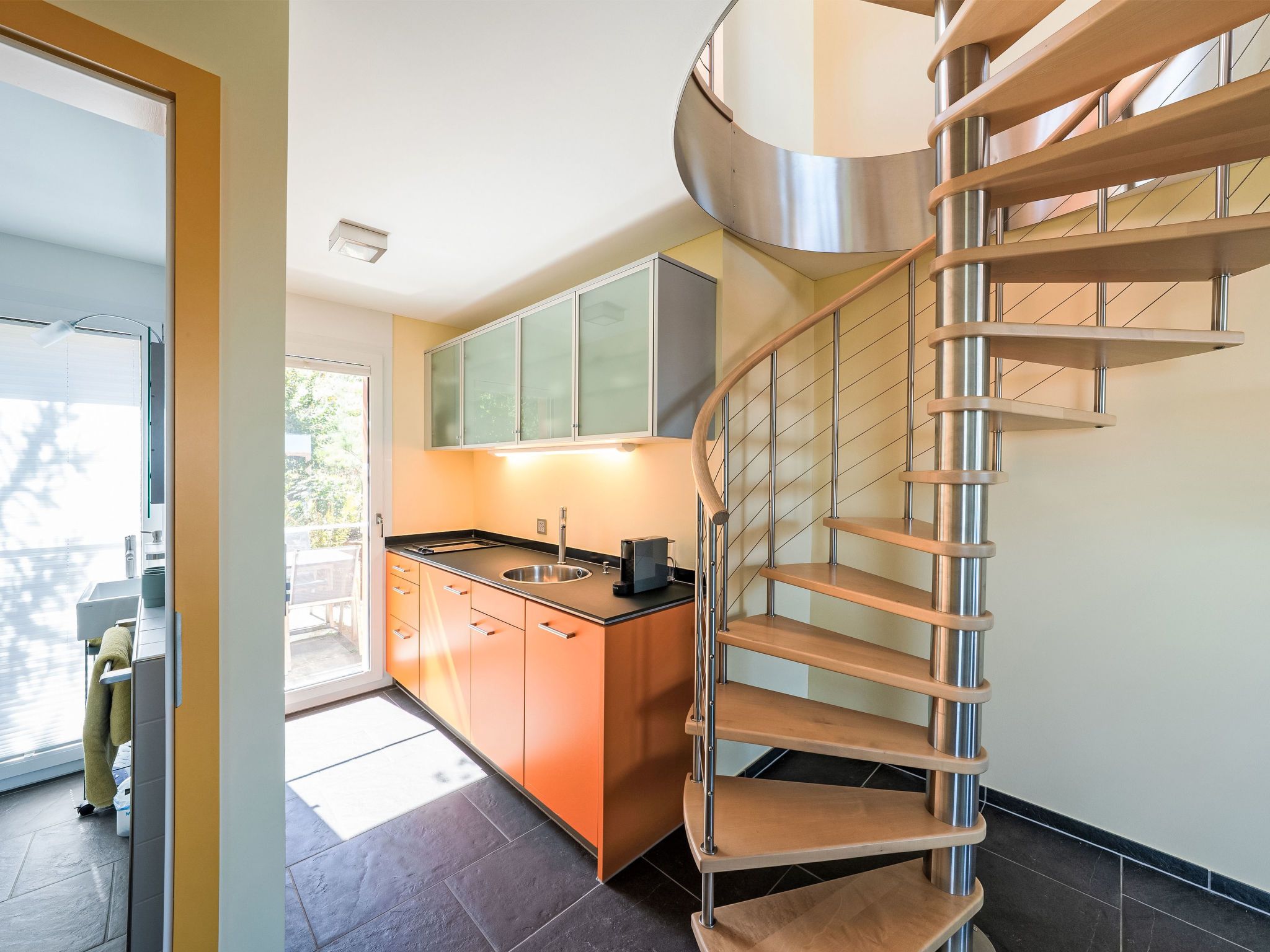 Une cuisine moderne équipée d’un four encastré, d’un évier et d’un escalier en acier inoxydable.