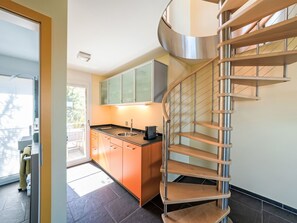 A modern kitchen with a built-in oven, a sink, and a stainless steel staircase.
