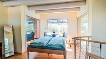 Une chambre avec un lit en bois, une vue sur l’extérieur, un balcon et un escalier.