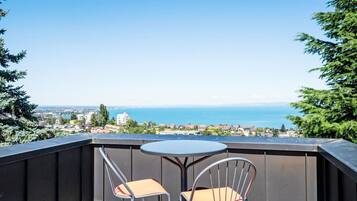 Un balcon avec une table et deux chaises, donnant sur un paysage urbain le long de la côte.