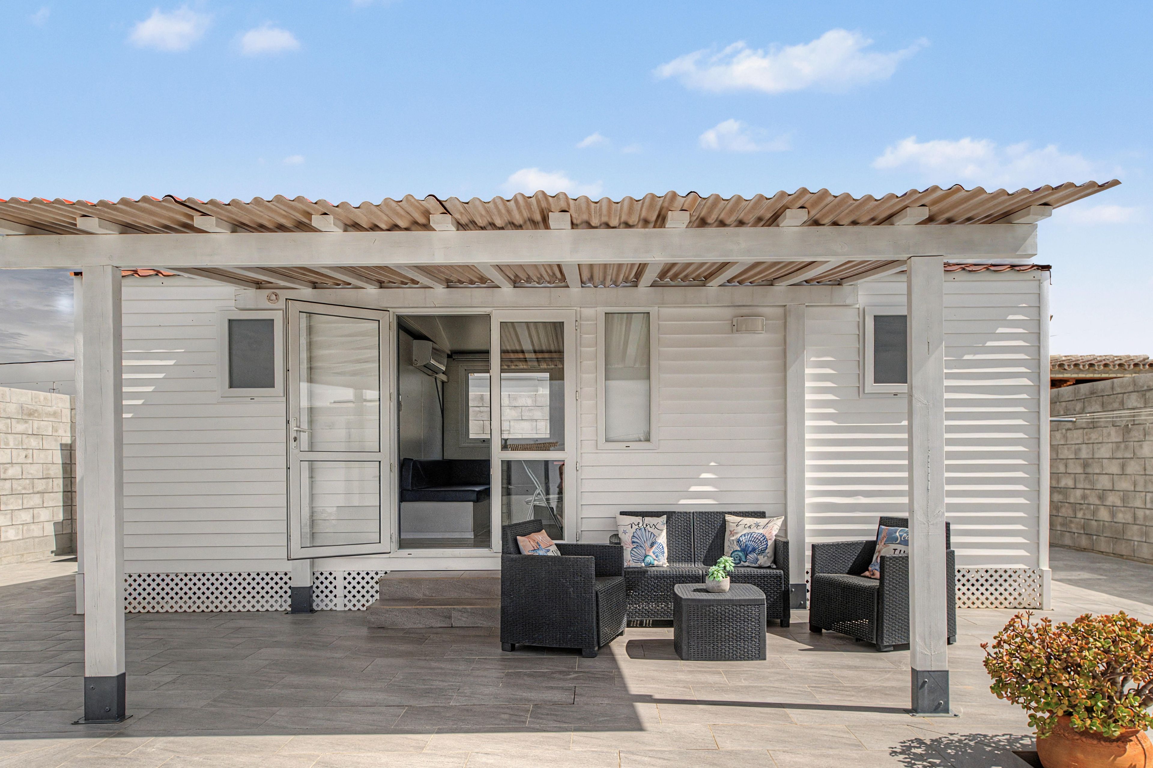 Un espace extérieur abrité, avec une pergola, une petite table et des chaises.