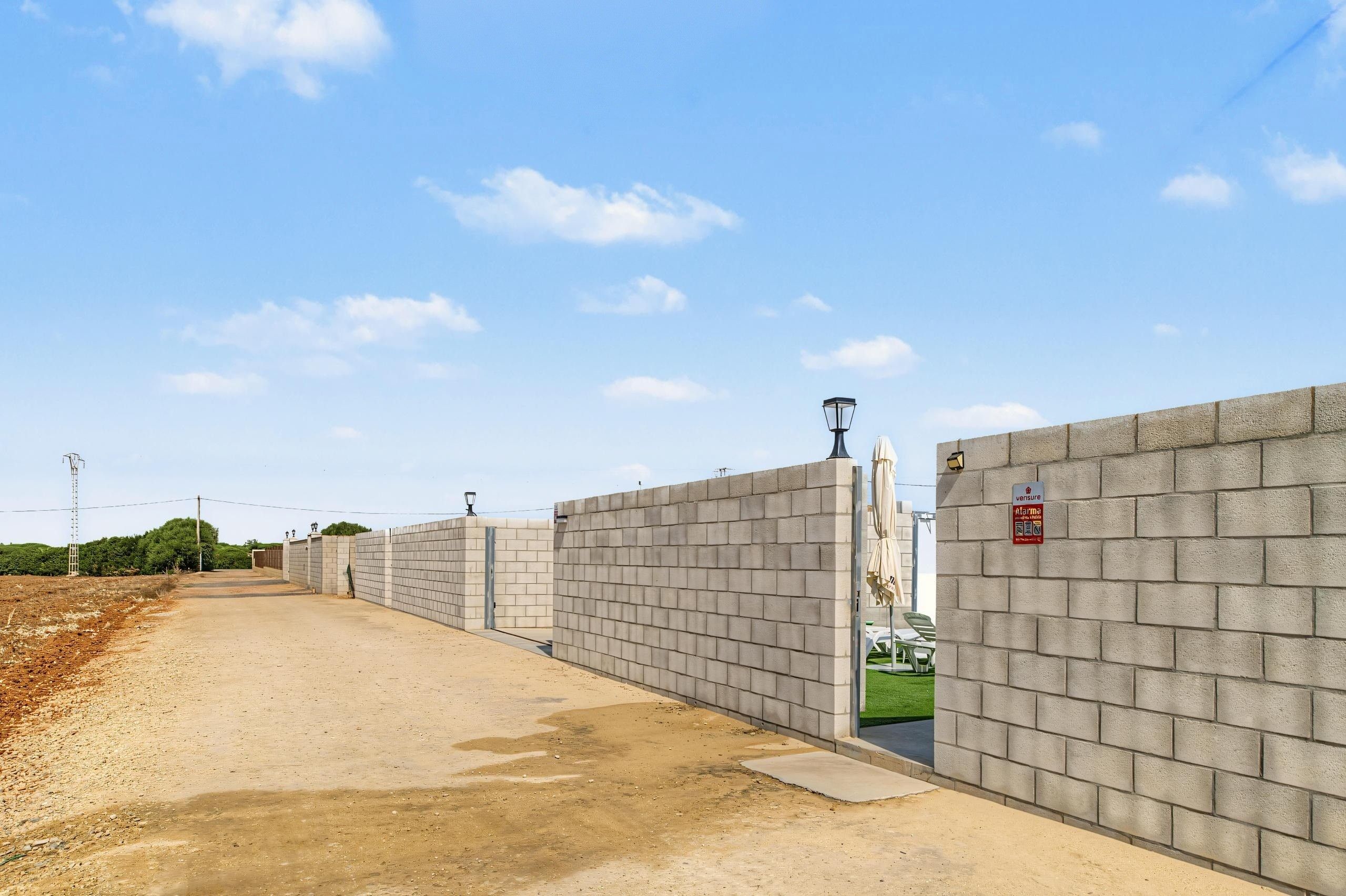 A paved pathway flanked by high concrete walls with a street lamp and a sign indicating a 5% VAT rate.