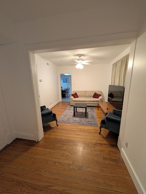 Un salon doté d’un parquet, d’un canapé, d’une table basse et d’un téléviseur.