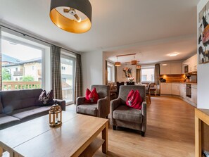 A modern living room with a sofa, armchairs, a wooden coffee table, and a dining area with a table and chairs. - Luxury chalet near Zell am See & Kaprun (Bruck an der Großglocknerstraße)
