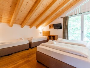 A hotel room with two beds, a wooden ceiling, a TV, and a window with curtains. - Luxury chalet near Zell am See & Kaprun (Bruck an der Großglocknerstraße)
