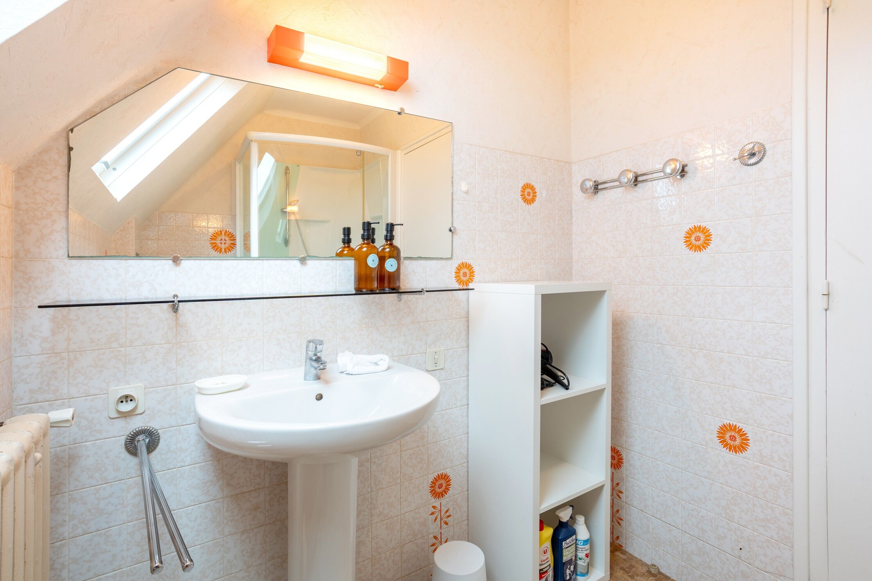 A bathroom with a white sink, mirror, and shelves with toiletries.
