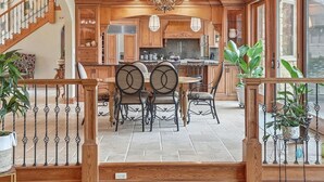 A spacious kitchen with wooden cabinets, a dining area with a table and chairs, and a staircase leading to an upper level.