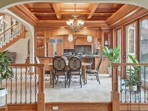 Una cocina amplia con armarios de madera, un comedor con mesa y sillas, y una escalera que lleva a un nivel superior.