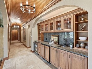 Una cocina con armarios de madera, encimeras de granito y una araña.