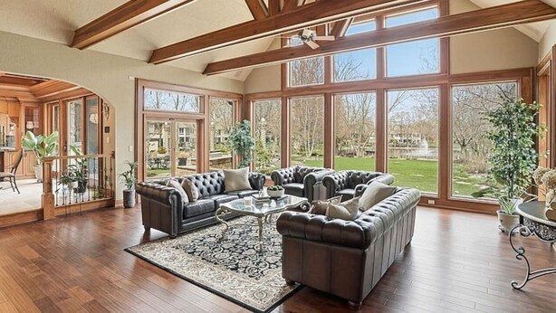 A spacious living room with a large sectional sofa, a coffee table, and a view of the outdoors through large windows.