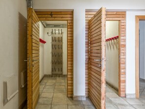 A hallway with wooden paneling, a tiled floor, and a door with a metal handle. - Holiday Apartment with a spa next to the gondola (Brixen im Thale)