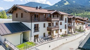 Ett hotell med flera våningar, balkonger, ett takförsett utomhusområde och utsikt över bergen.