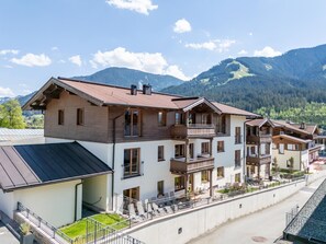 A multi-story hotel with balconies, a covered outdoor area, and a view of mountains. - Holiday Apartment with a spa next to the gondola (Brixen im Thale)