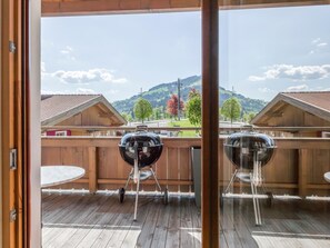 An outdoor deck with two barbecue grills, wooden fencing, and a view of a mountainous landscape. - Luxury apartment with wellness next to gondola (Brixen im Thale)